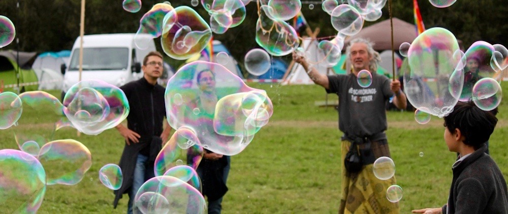 Mehrere jüngere und ältere Leute auf einer Wiese lassen Riesenseifenblasen steigen