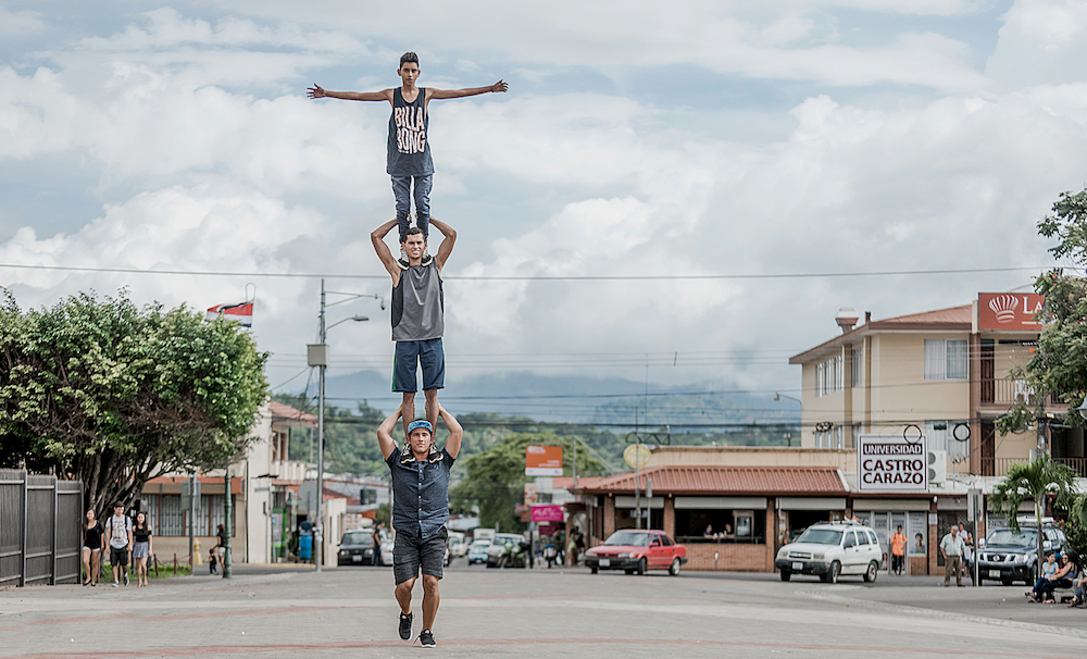 Drei junge Männer stehen einander auf den Schultern auf einer Strasse in Costa Rica