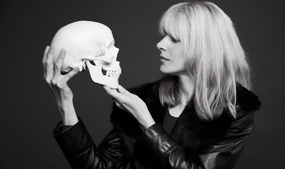 Schwarzweiss-Bild mit einer jungen blonden Frau im Profil, die beiden Händen einen Totenschädel hält