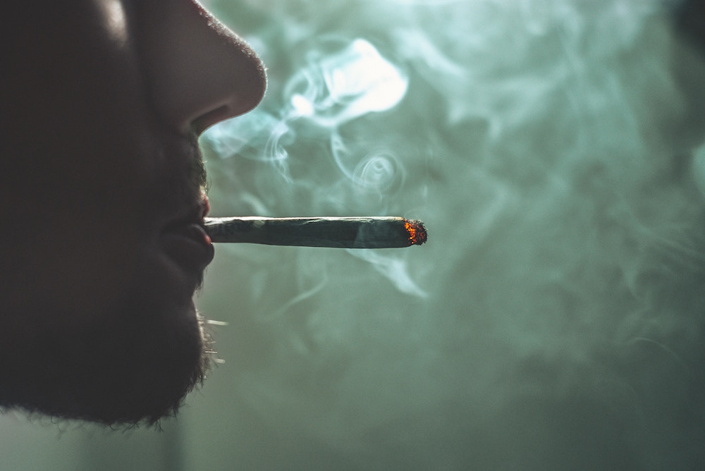 Gesicht eines jungen Mannes im Profil, der einen Joint raucht