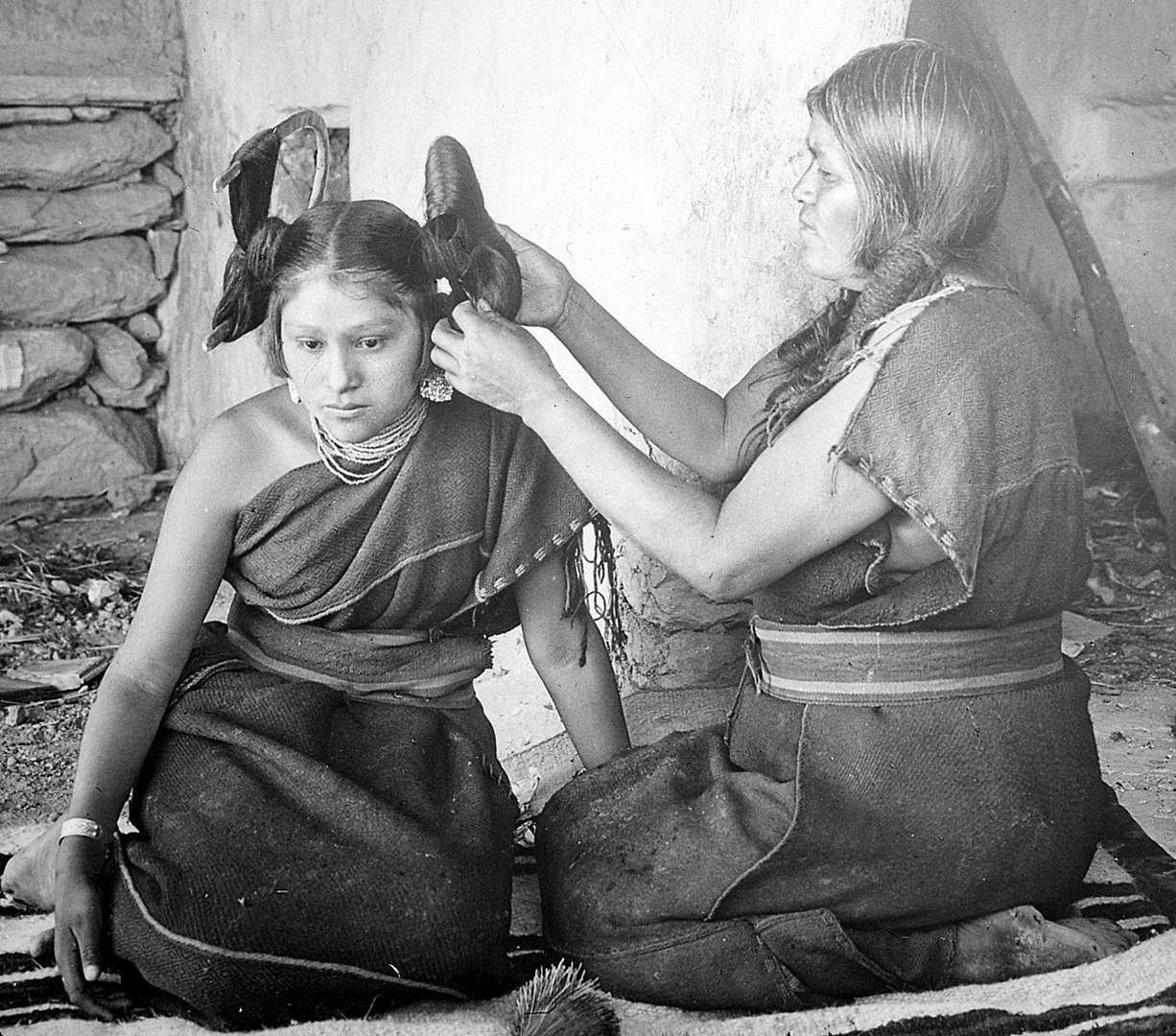 CC: Eine Hopi bindet das Haar eines unverheirateten Mädchens zur traditionellen „Schmetterlingsfrisur“ (um 1900)