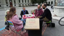 Fünf Leute sitzen an einem runden Tisch auf einem Parkplatz