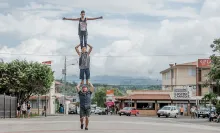 Drei junge Männer stehen einander auf den Schultern auf einer Strasse in Costa Rica