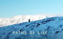 Eine Person in verschneiter Berglandschaft, die einen Hang hinauf geht